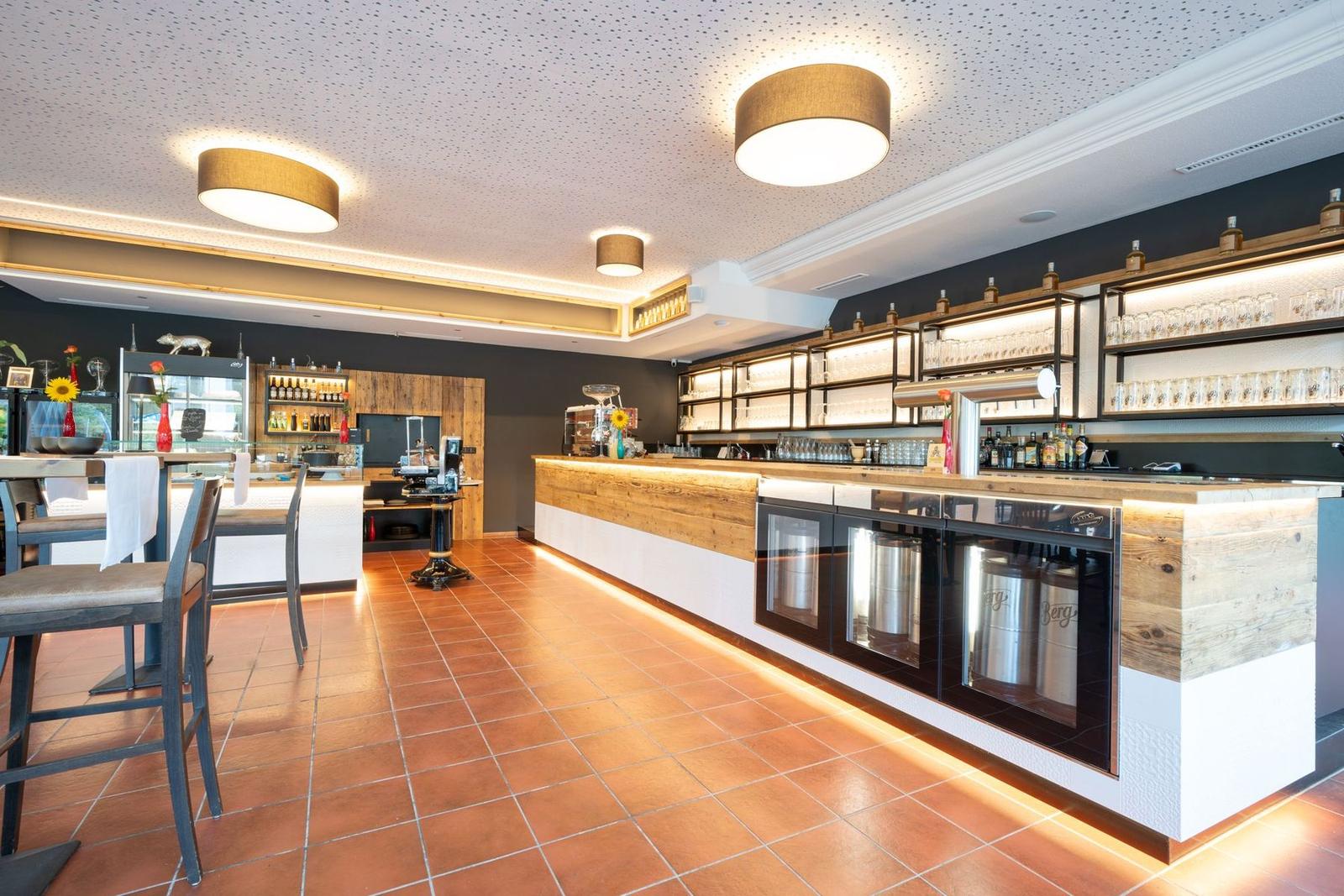 Gastraum mit beleuchteter Bar aus Altholz und Terrakottaboden